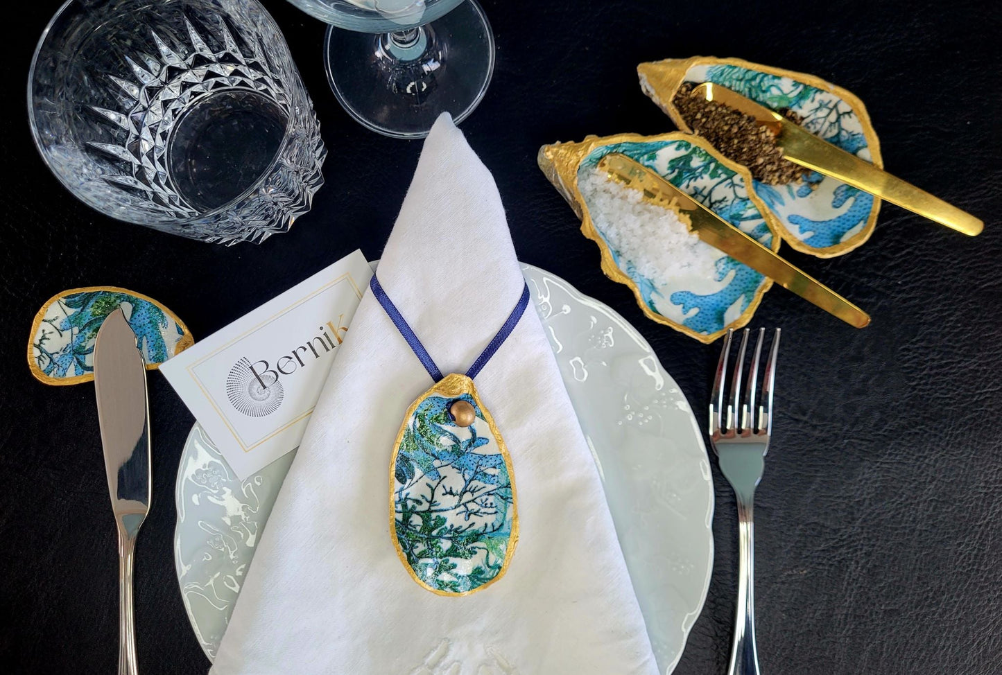 Porte couteau en coquille d'huître, camaïeu de bleu-vert et motifs corail marin, parfait pour des repas élégants en bord de mer.