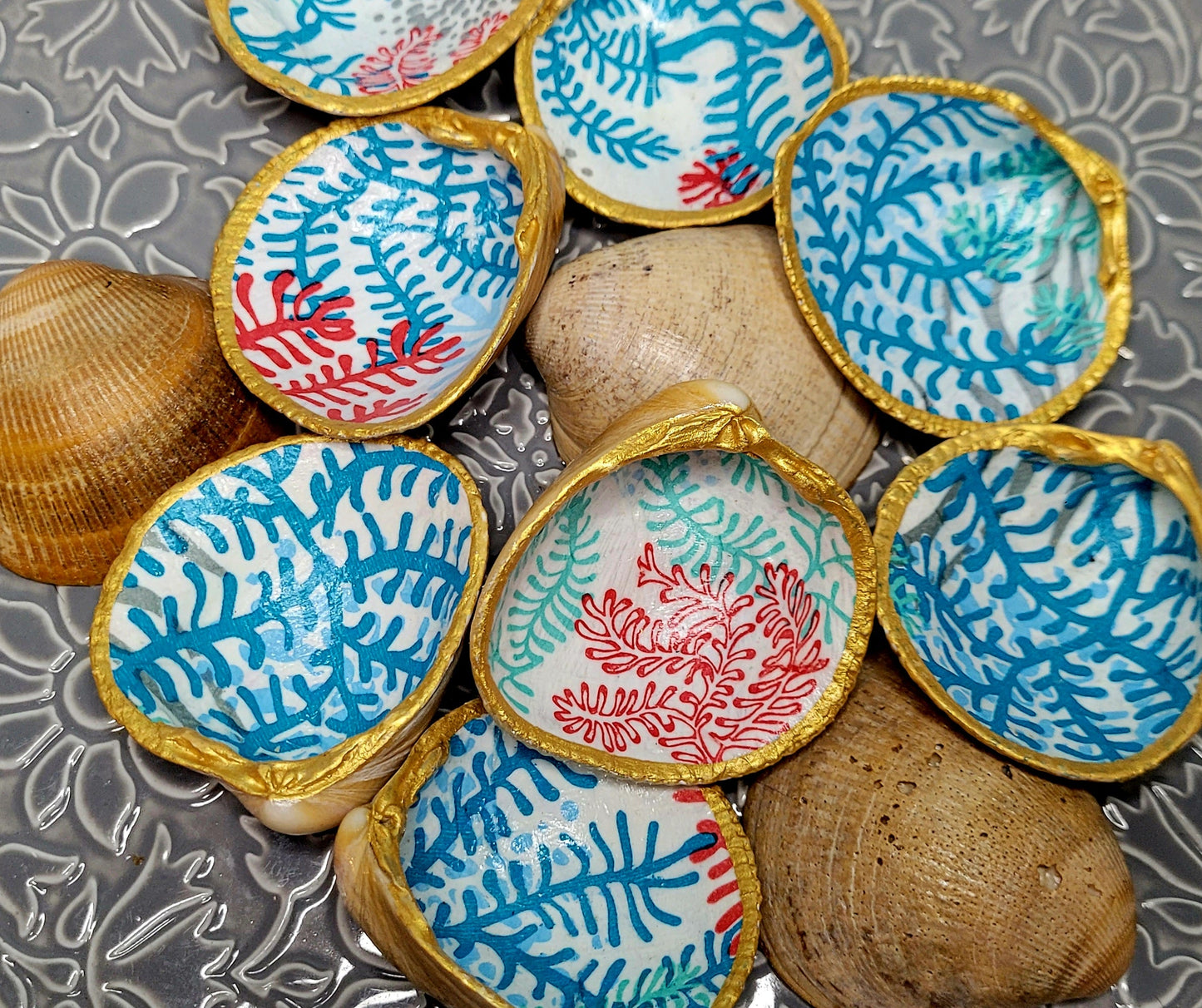 Décoration artisanale : coquillage bucarde orné de motifs corail en bleu et rouge, issu de la collection Océane.