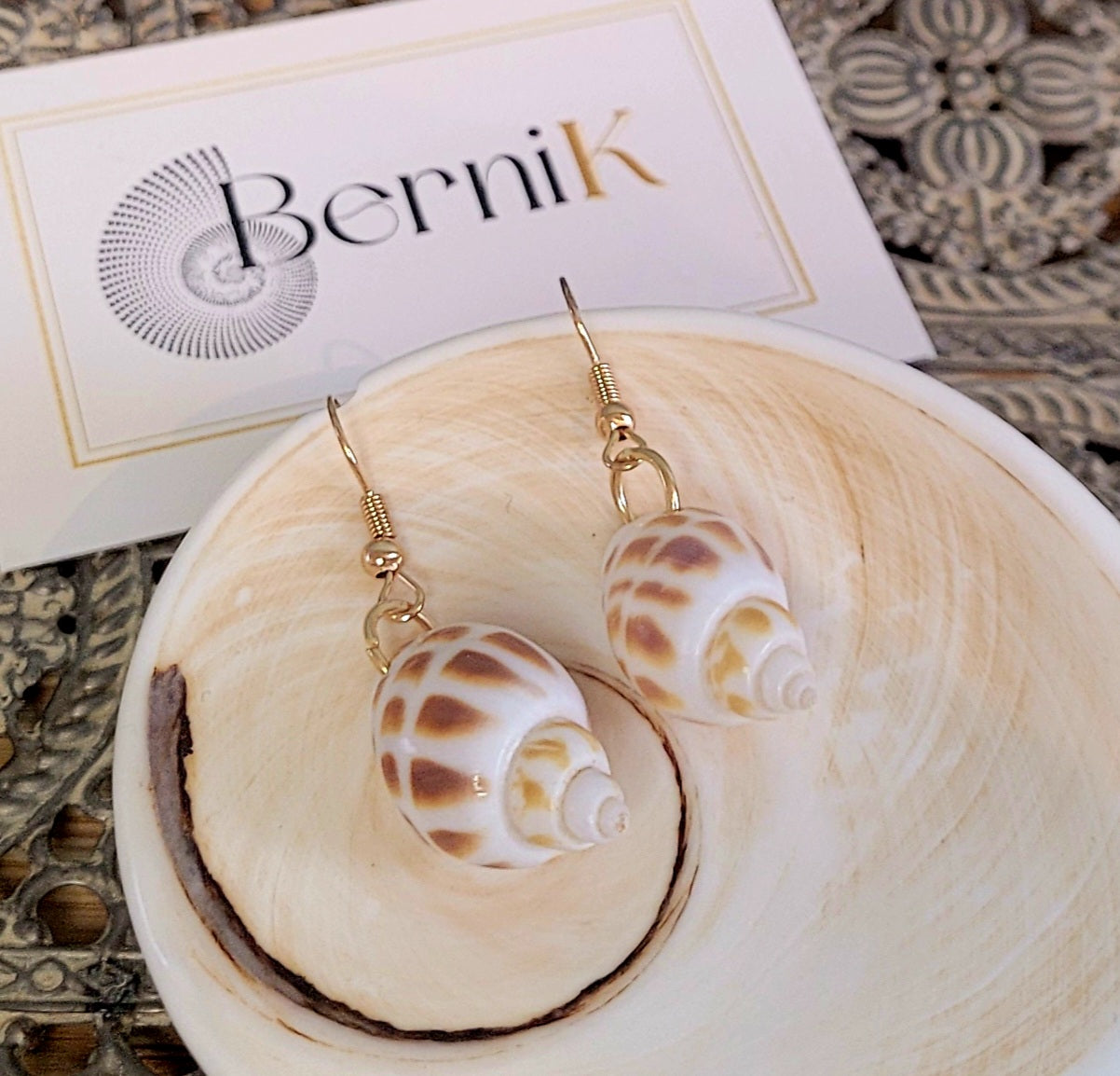 Boucles d'oreilles en coquillage blanc tacheté montées sur crochets en acier inoxydable doré, style naturel et raffiné.