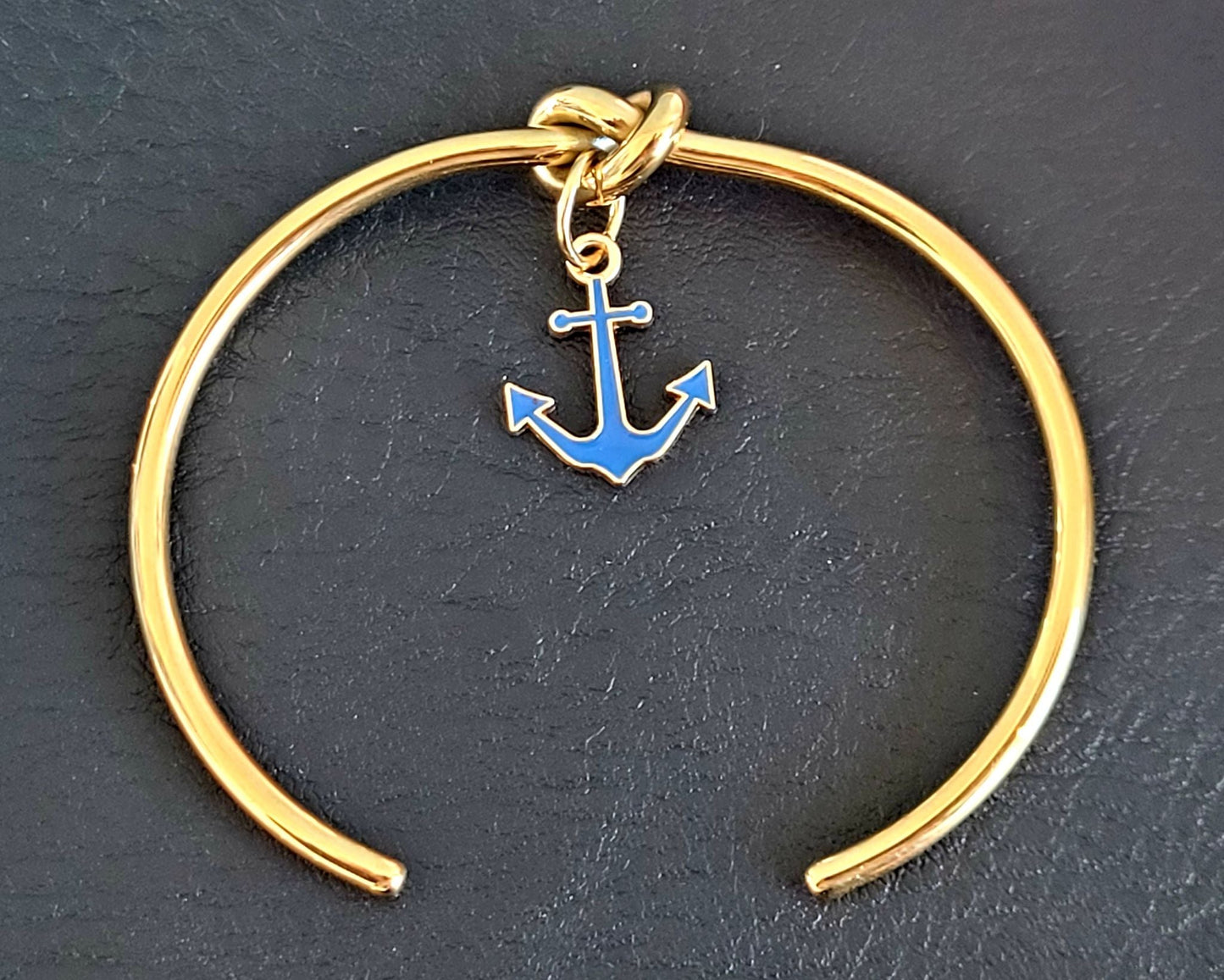 Bracelet jonc chic en acier inoxydable doré, décoré d'une breloque ancre bleue, parfait pour les amateurs de mer.