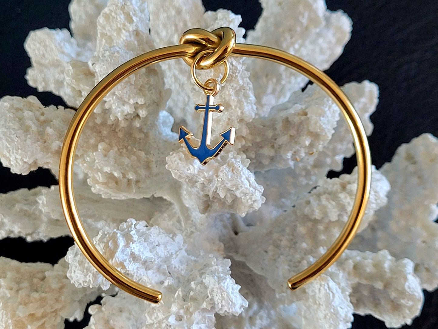 Bracelet jonc en acier inoxydable doré avec nœud marin et breloque ancre bleue, élégant design maritime.