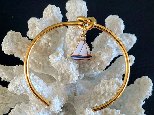 Bracelet jonc en acier inoxydable doré avec nœud marin et breloque bateau bleu et doré, design maritime.