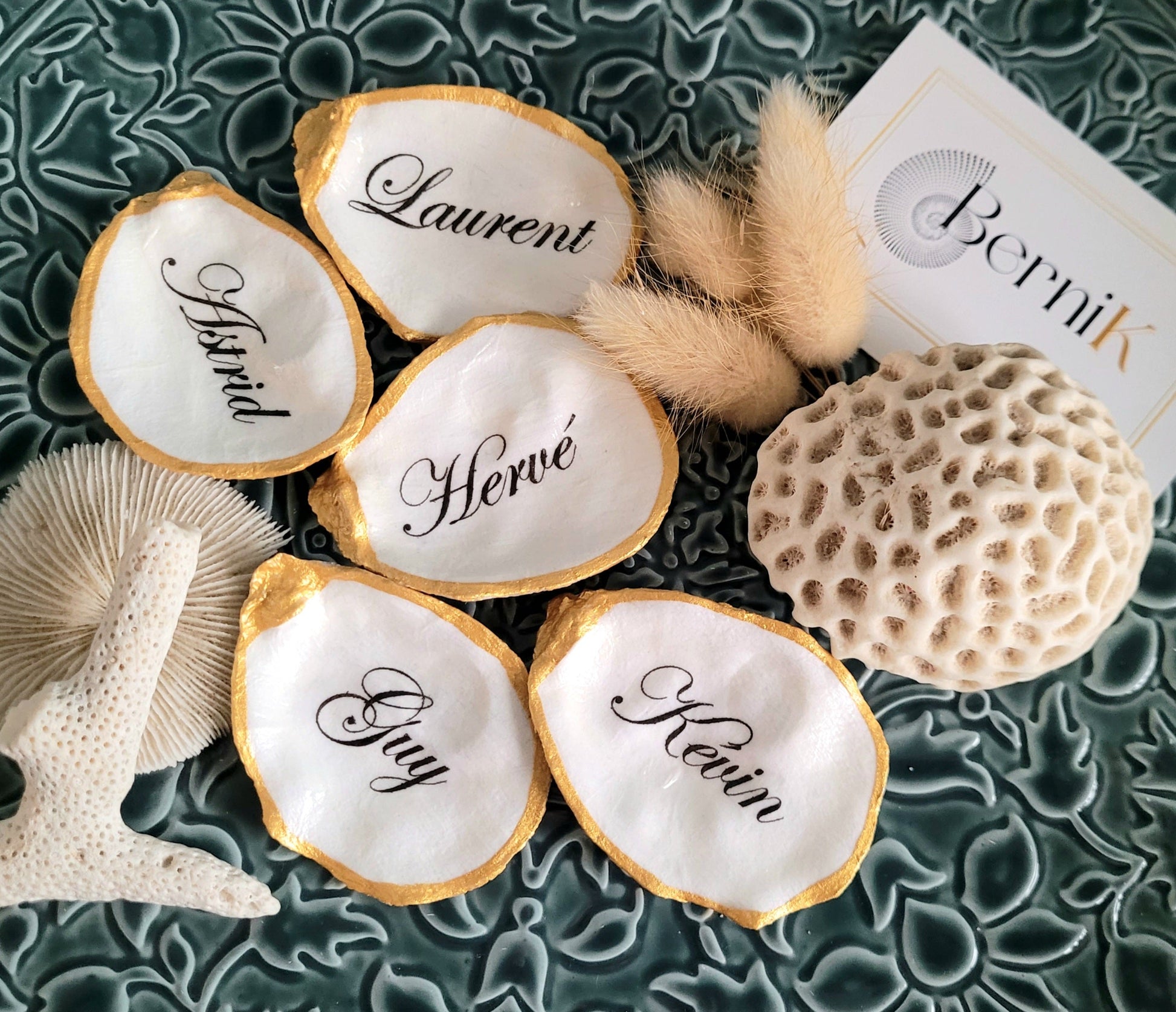 Marque-place artisanal en coquille d’huître décorée à la main, personnalisable avec le prénom des invités.