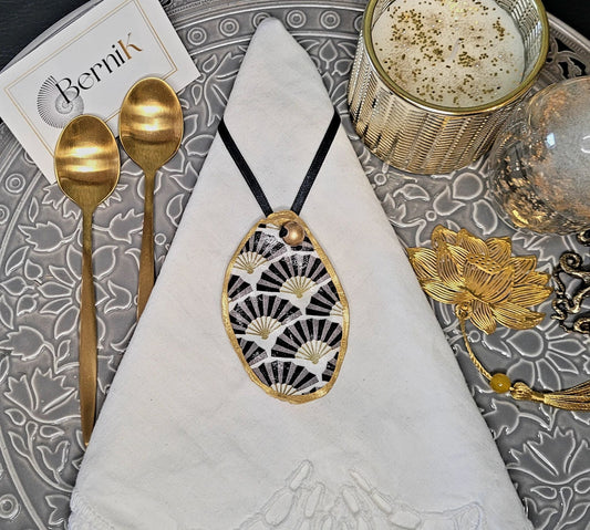 Ronds de serviette en coquilles d'huître ornées de motifs Art Déco noirs et dorés, pour une table élégante et raffinée.