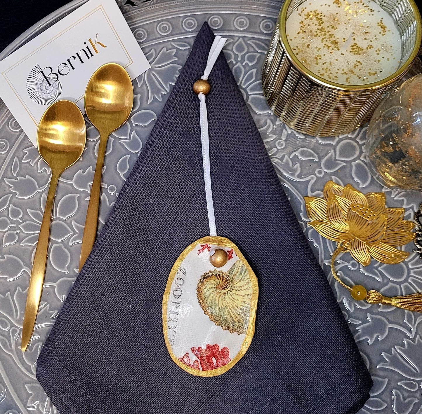 Accessoires de table artisanaux : ronds de serviette en coquille d'huître avec corail rouge et coquillage pour un dîner raffiné.