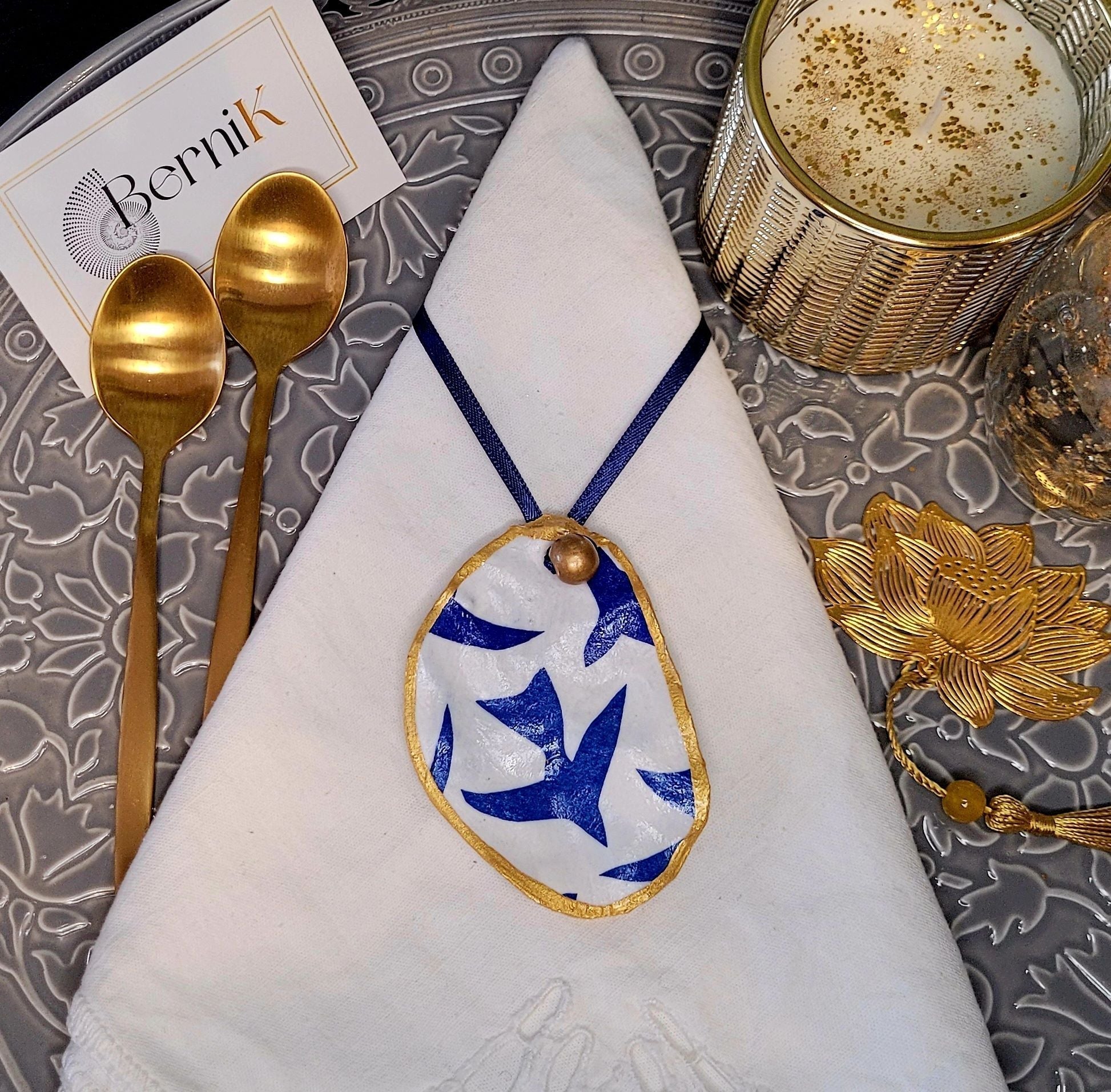 Accessoire de table artisanal en coquille d’huître avec design oiseaux bleus.